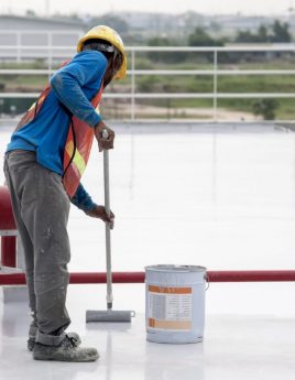 Construction worker coating epoxy paint at roof slab for water proof protection